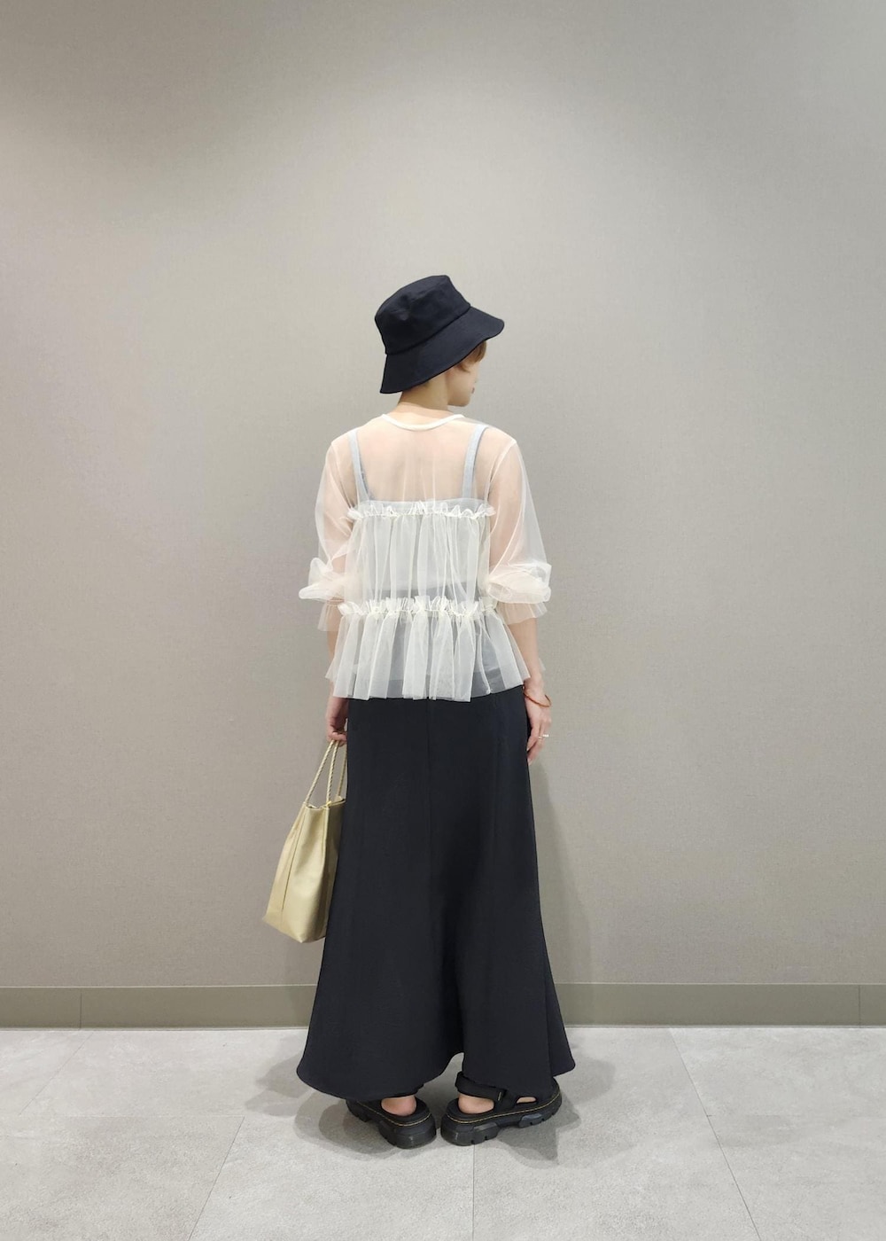 グレー系のタンクトップ、ホワイト系のカーディガン/ボレロ、ゴールド系のトートバッグを着用したレディースの夏コーディネートの4枚目の写真