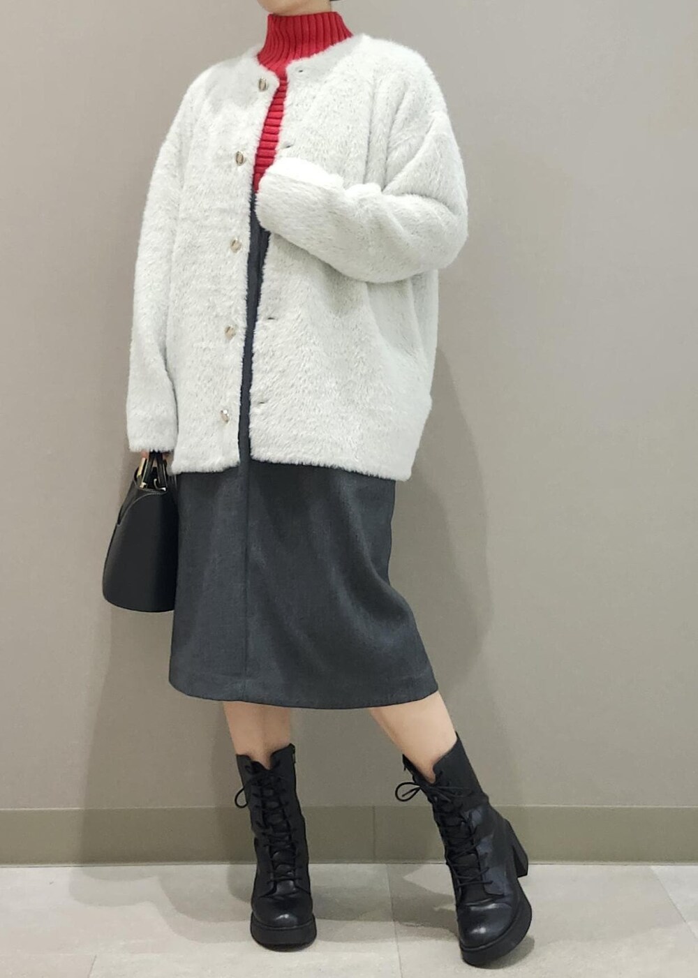 グレー系のジャンパースカート、ホワイト系のその他アウター、レッド系のニット/セーターを着用したレディースの秋コーディネートの2枚目の写真