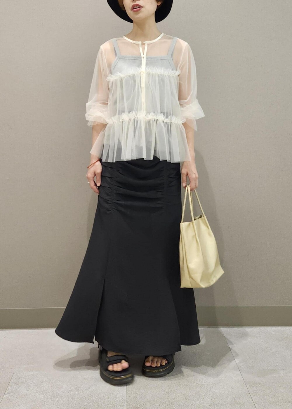 グレー系のタンクトップ、ホワイト系のカーディガン/ボレロ、ゴールド系のトートバッグを着用したレディースの夏コーディネートの5枚目の写真