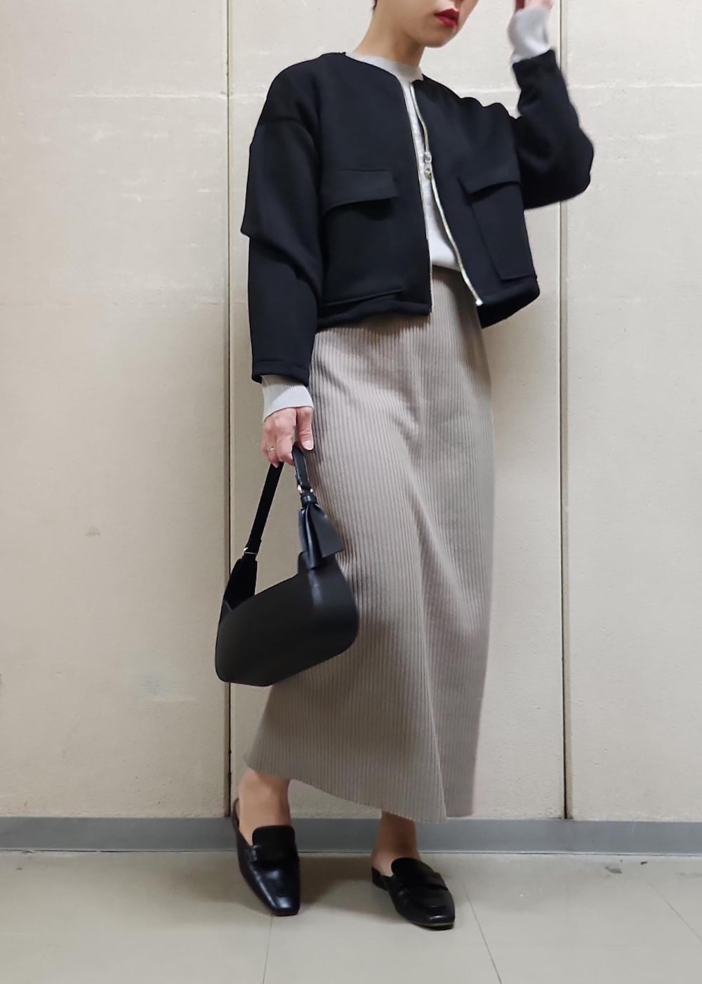 ブラック系のハンドバッグ、ブラウン系のスカート、グレー系のニット/セーターを着用したレディースの春コーディネートの5枚目の写真