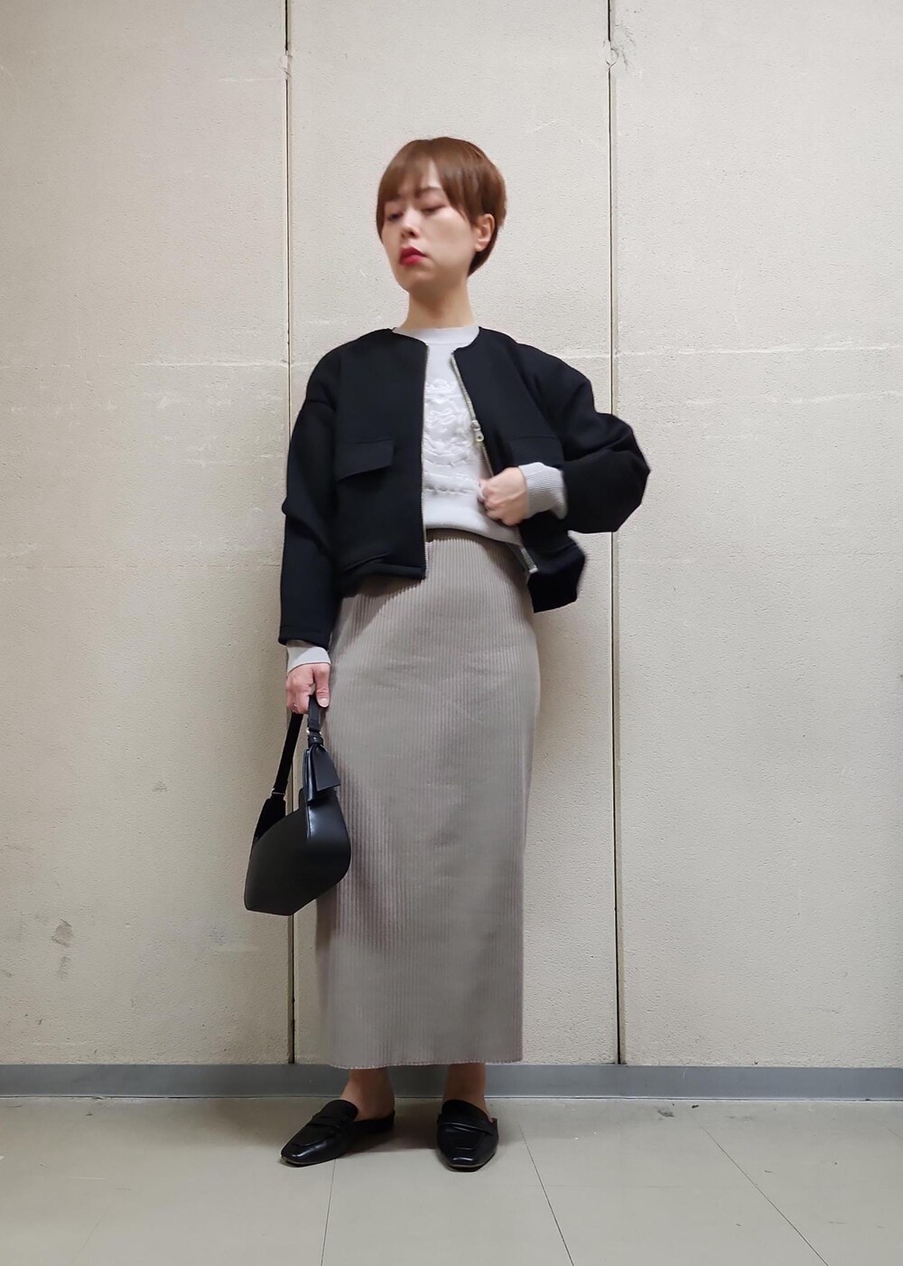 ブラック系のハンドバッグ、ブラウン系のスカート、グレー系のニット/セーターを着用したレディースの春コーディネートの6枚目の写真