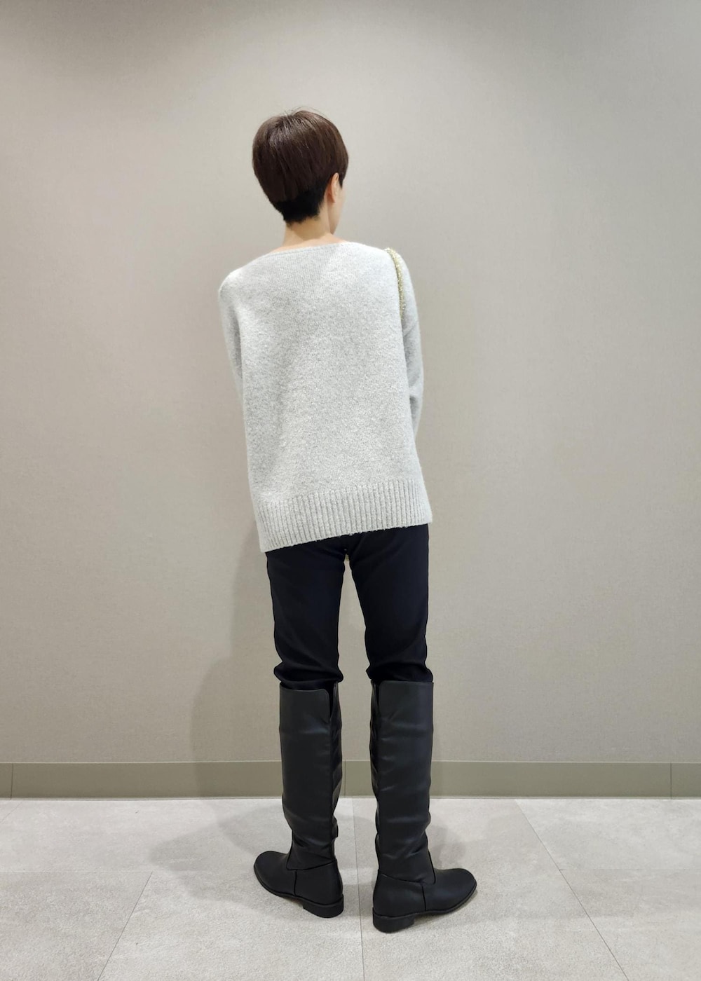 ブラック系のブーツ、ゴールド系のショルダーバッグ、グレー系のニット/セーターを着用したレディースの秋コーディネートの2枚目の写真