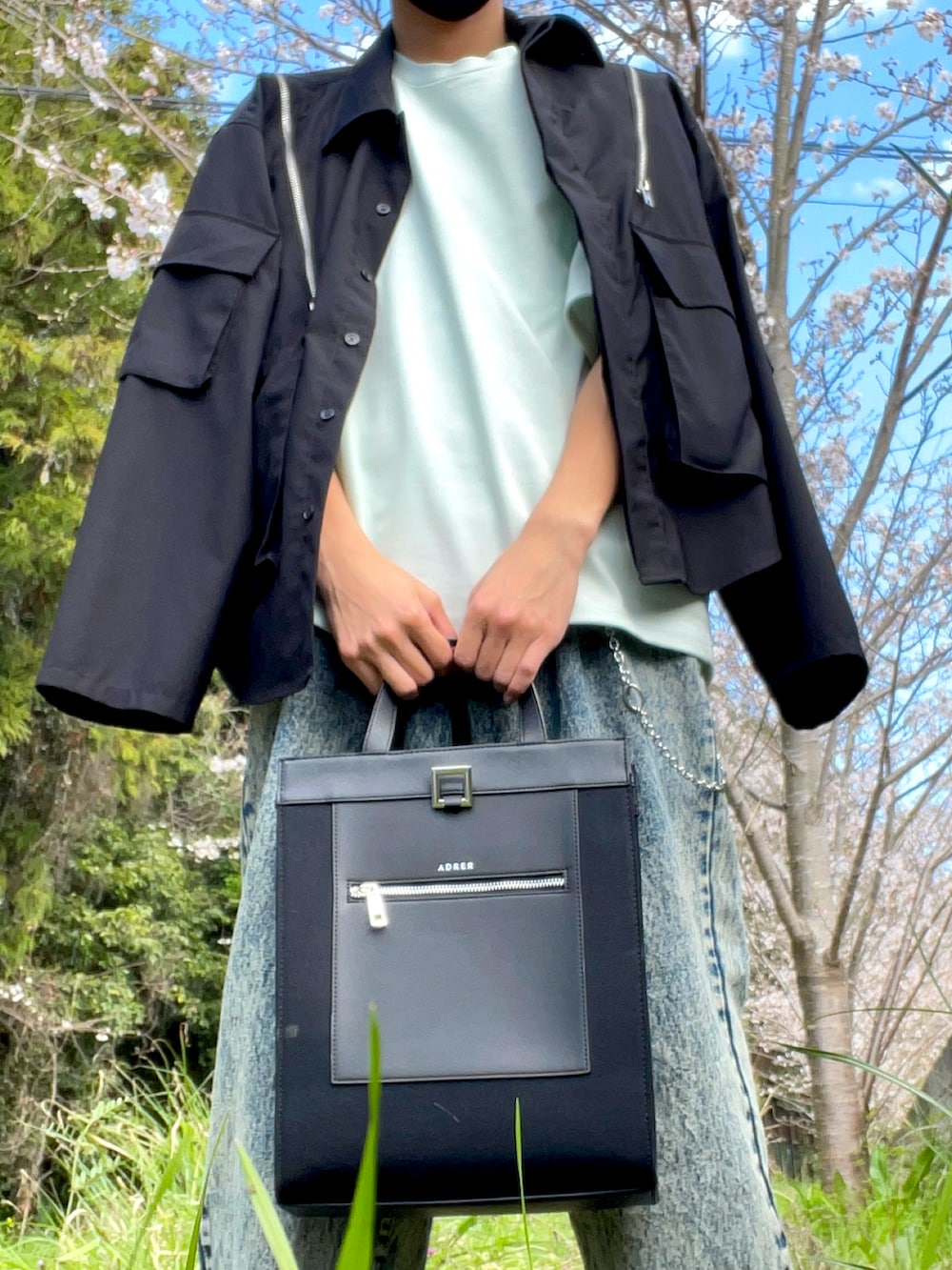 ブラック系のトートバッグ、ベージュ系のデニムパンツ、ブラック系のその他アウターを着用したメンズの春コーディネートの2枚目の写真