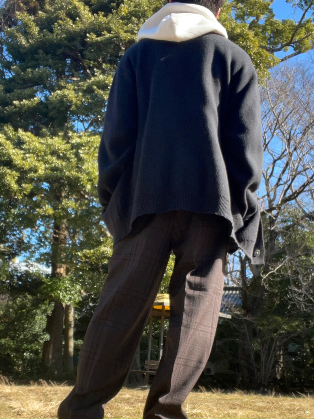 ブラウン系のスラックス、ブラック系のスニーカー、ホワイト系のパーカーを着用したメンズの冬コーディネートの4枚目の写真