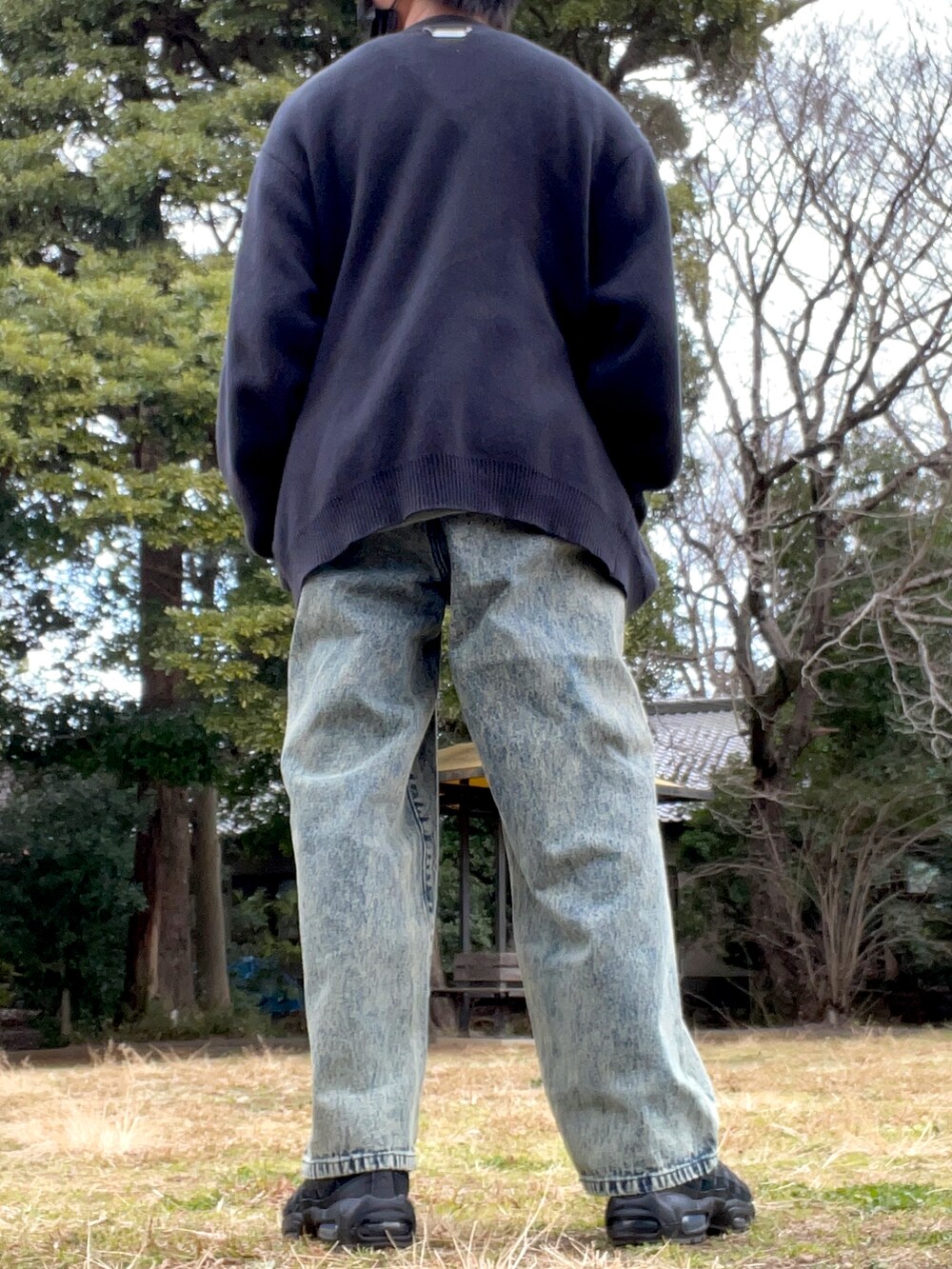 ブラック系のショルダーバッグ、ブラック系のカーディガン/ボレロ、ベージュ系のデニムパンツを着用したメンズの冬コーディネートの3枚目の写真