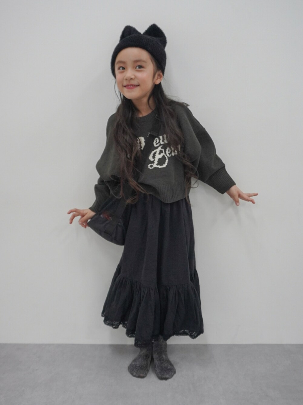 グレー系のトップス、ブラック系のスカート、ブラック系のショルダーバッグを着用したキッズの冬コーディネートの3枚目の写真