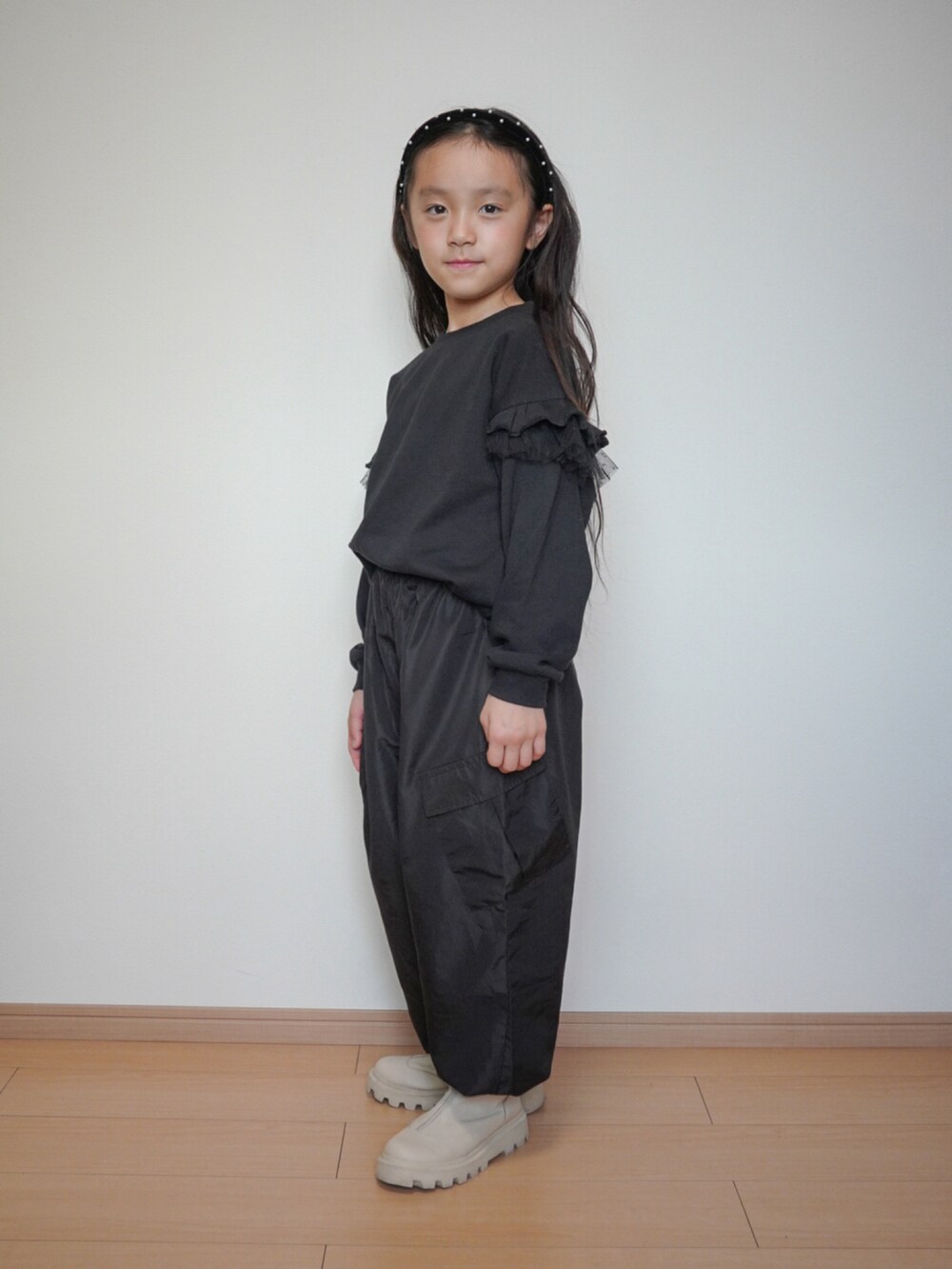 ブラック系のスウェット、ブラック系のカーゴパンツ、ホワイト系のブーツを着用したキッズの秋コーディネートの3枚目の写真
