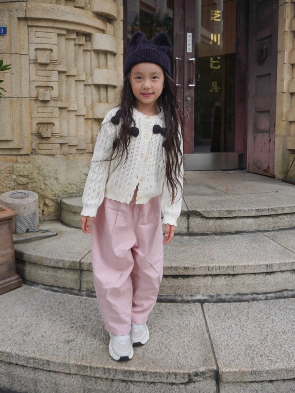 ホワイト系のカーディガン/ボレロ、ピンク系のカーゴパンツ、グレー系のスニーカーを着用したキッズの秋コーディネートの2枚目の写真