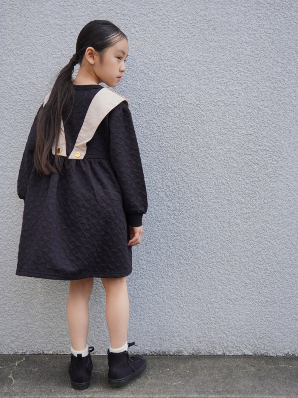 ブラック系のワンピース、ブラック系のスニーカー、ホワイト系のソックス/靴下を着用したキッズの冬コーディネートの3枚目の写真