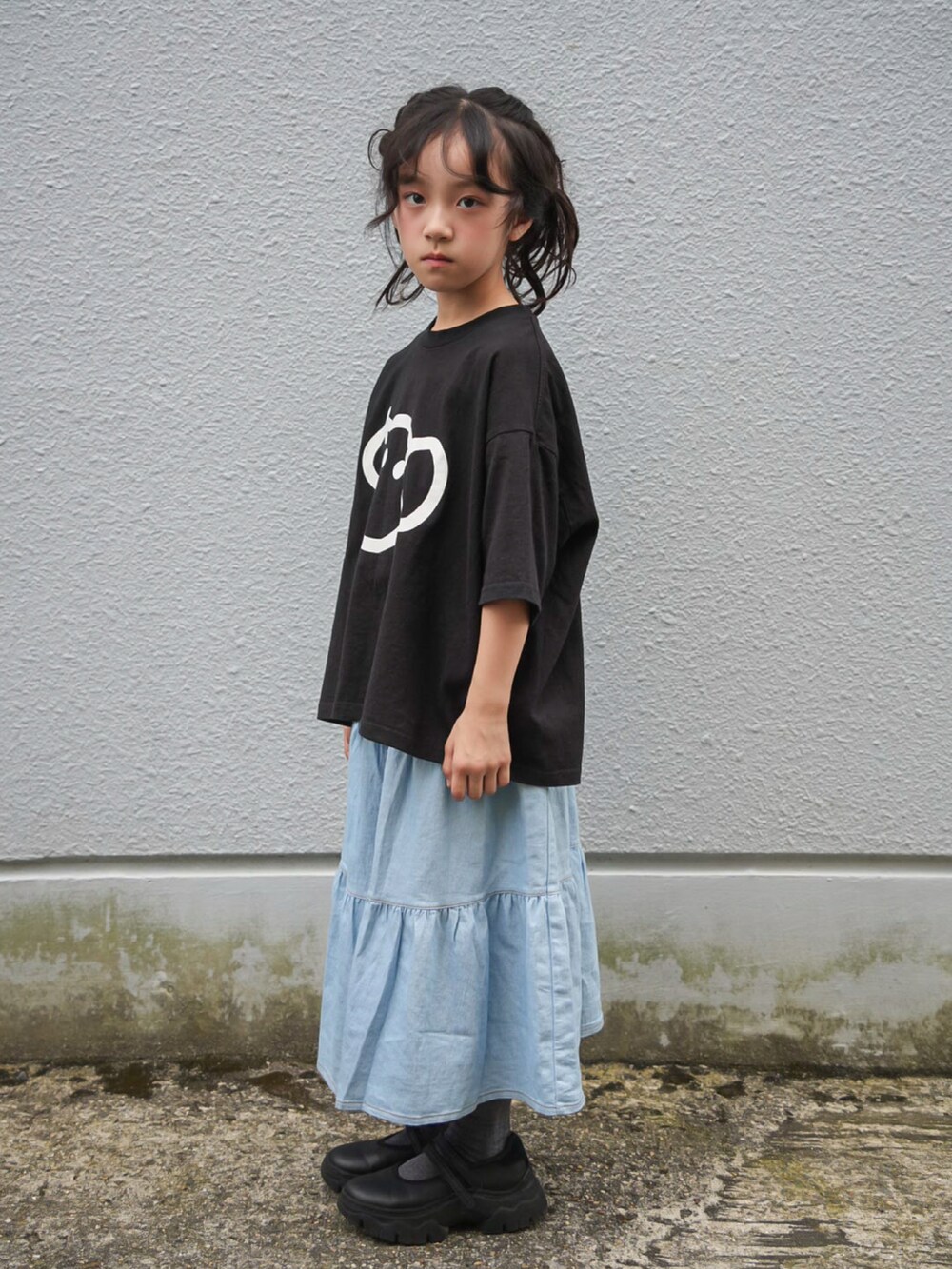 ブルー系のデニムスカート、ブラック系のTシャツ/カットソー、ブラック系のスニーカーを着用したキッズの秋コーディネートの3枚目の写真