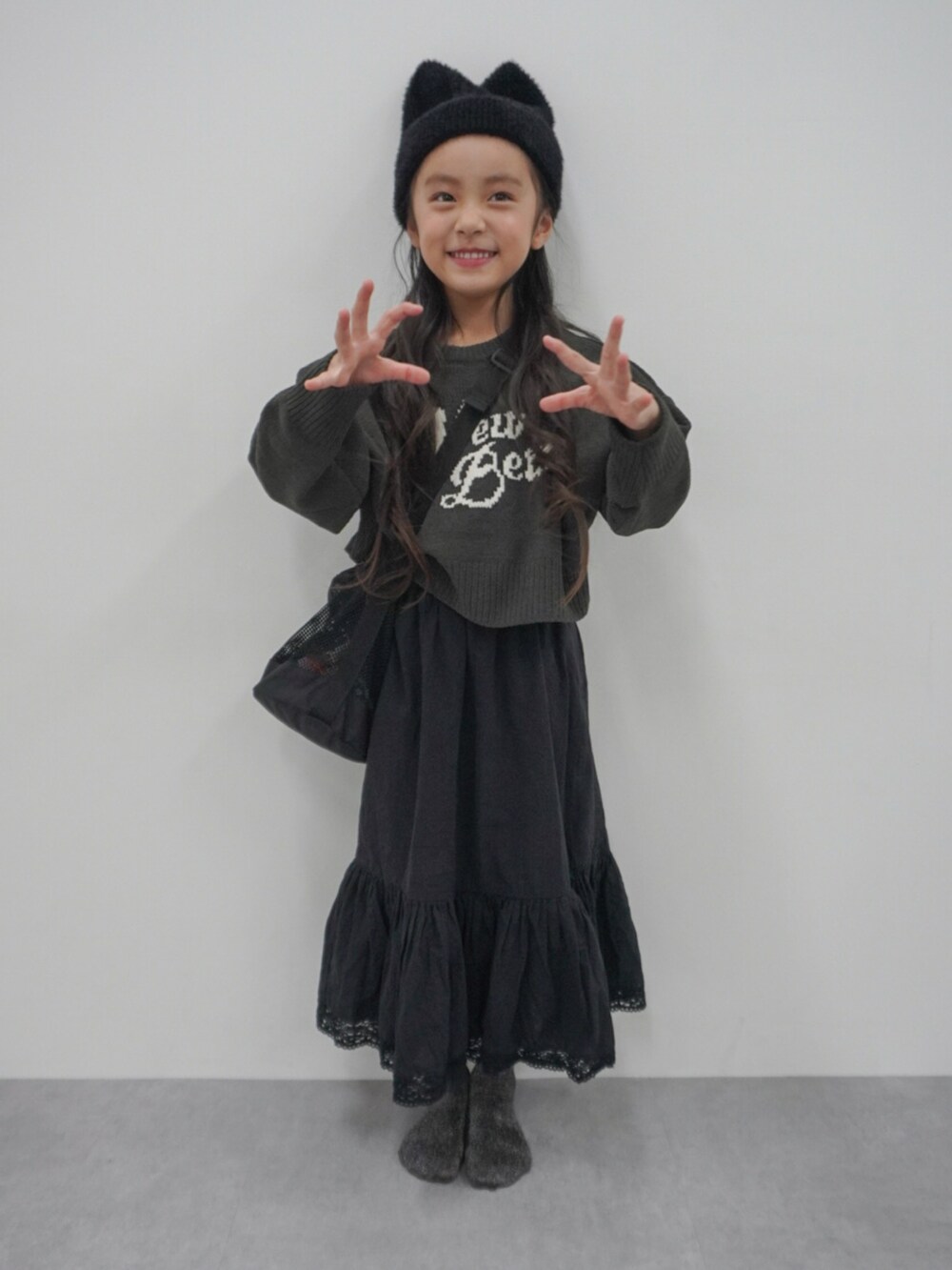 グレー系のトップス、ブラック系のスカート、ブラック系のショルダーバッグを着用したキッズの冬コーディネートの2枚目の写真