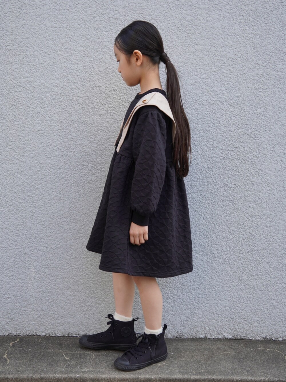 ブラック系のワンピース、ブラック系のスニーカー、ホワイト系のソックス/靴下を着用したキッズの冬コーディネートの2枚目の写真