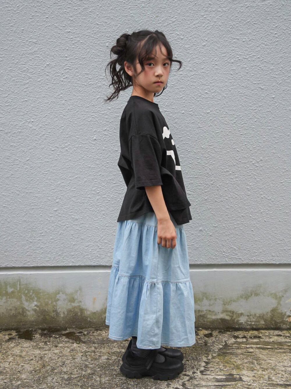 ブルー系のデニムスカート、ブラック系のTシャツ/カットソー、ブラック系のスニーカーを着用したキッズの秋コーディネートの2枚目の写真