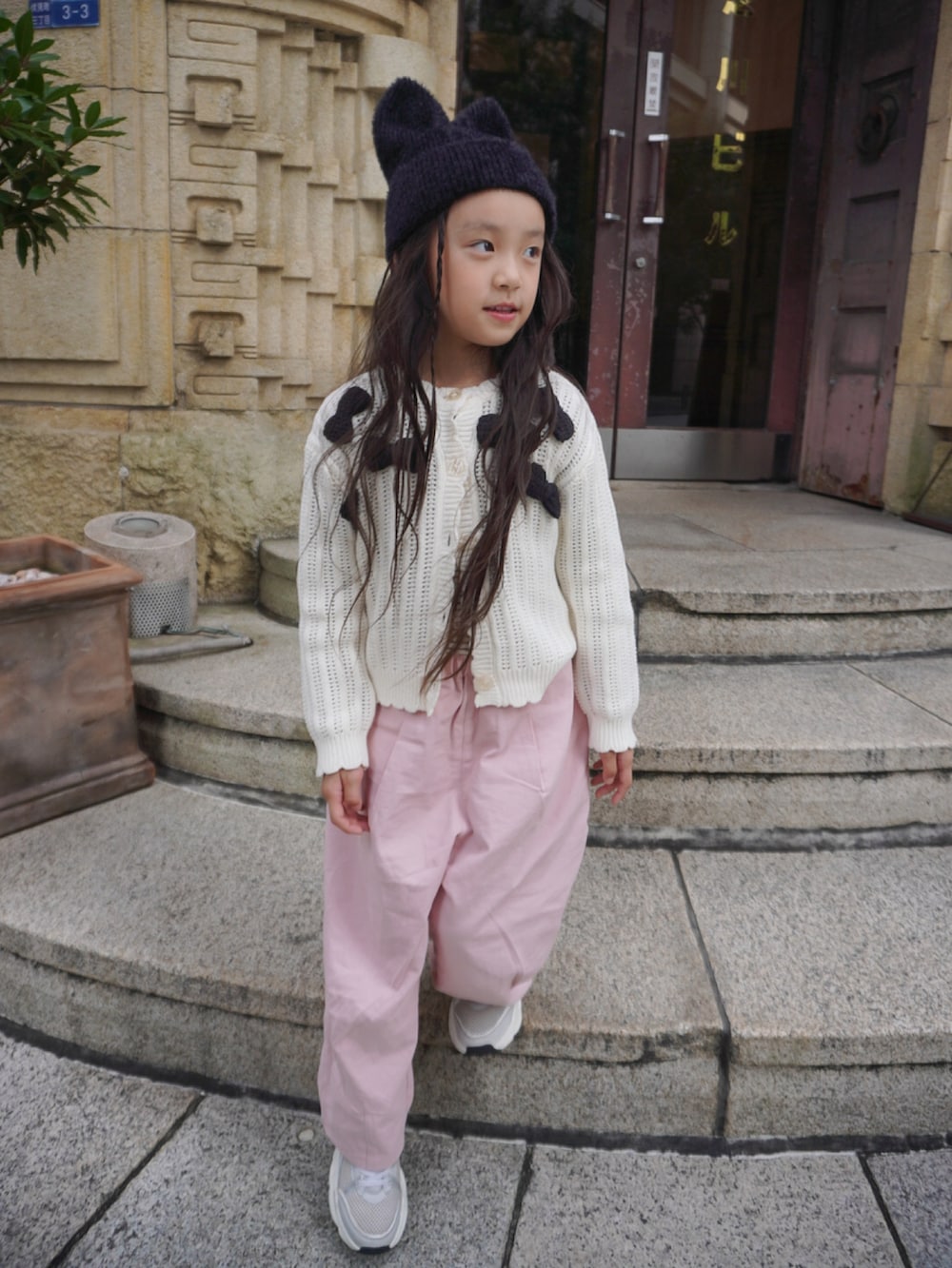 ホワイト系のカーディガン/ボレロ、ピンク系のカーゴパンツ、グレー系のスニーカーを着用したキッズの秋コーディネートの3枚目の写真