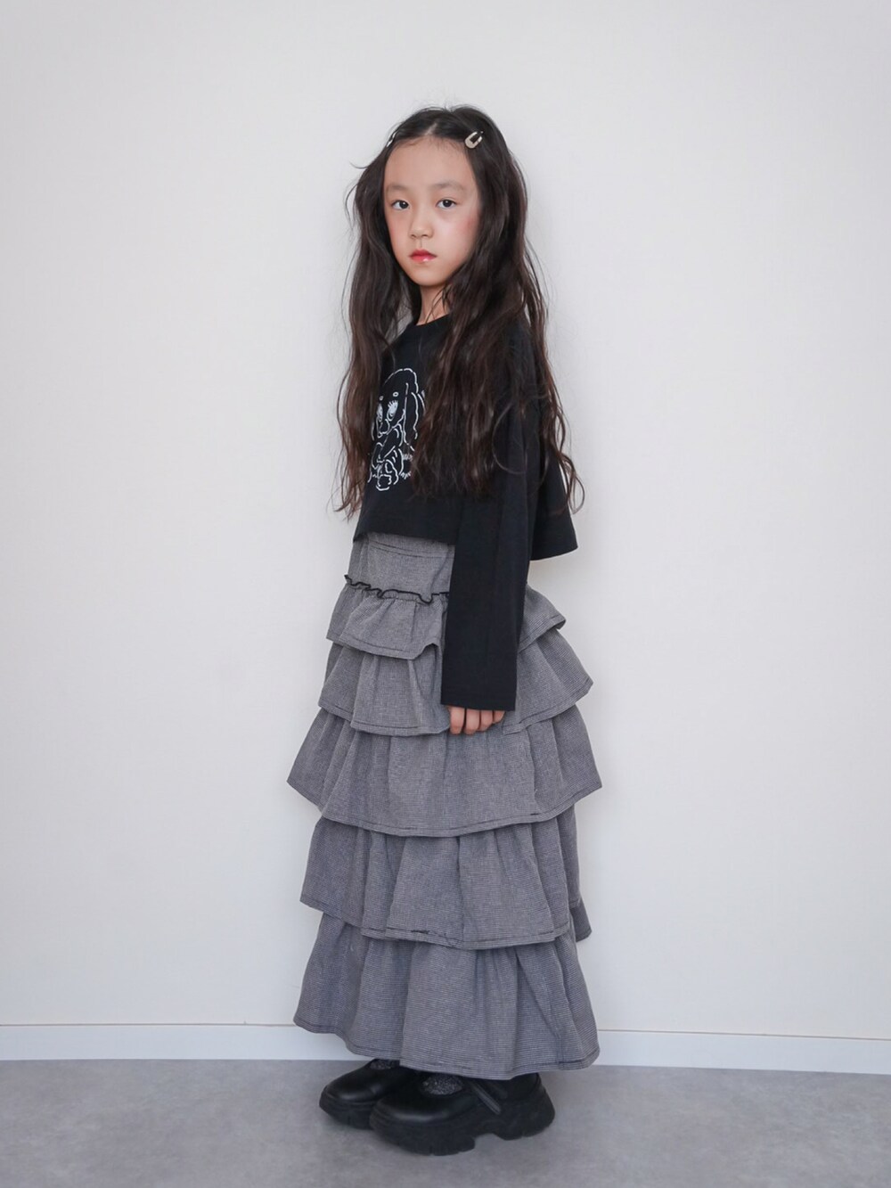 ブラック系のTシャツ/カットソー、グレー系のスカート、ブラック系のスニーカーを着用したキッズの秋コーディネートの3枚目の写真