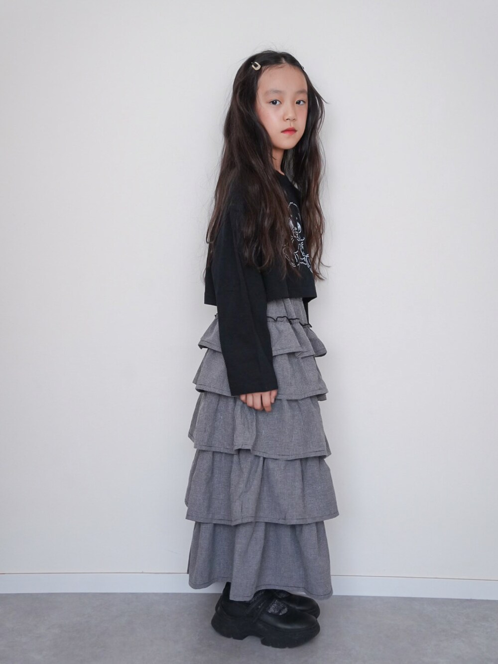 ブラック系のTシャツ/カットソー、グレー系のスカート、ブラック系のスニーカーを着用したキッズの秋コーディネートの2枚目の写真