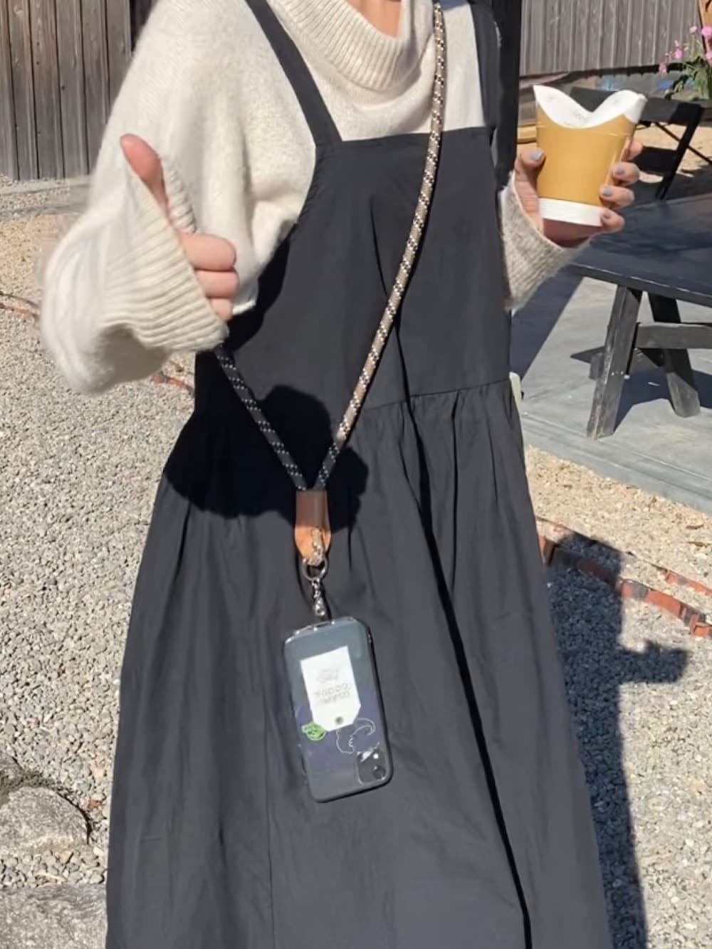 ベージュ系のニット/セーター、ブラック系のワンピース、グリーン系のスマホグッズを着用したレディースの秋コーディネートの2枚目の写真