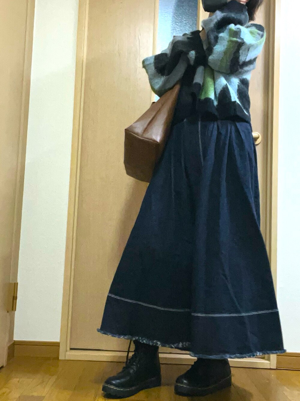 ブルー系のデニムスカート、ブラック系のブーツ、グリーン系のニット/セーターを着用したレディースの春コーディネートの3枚目の写真