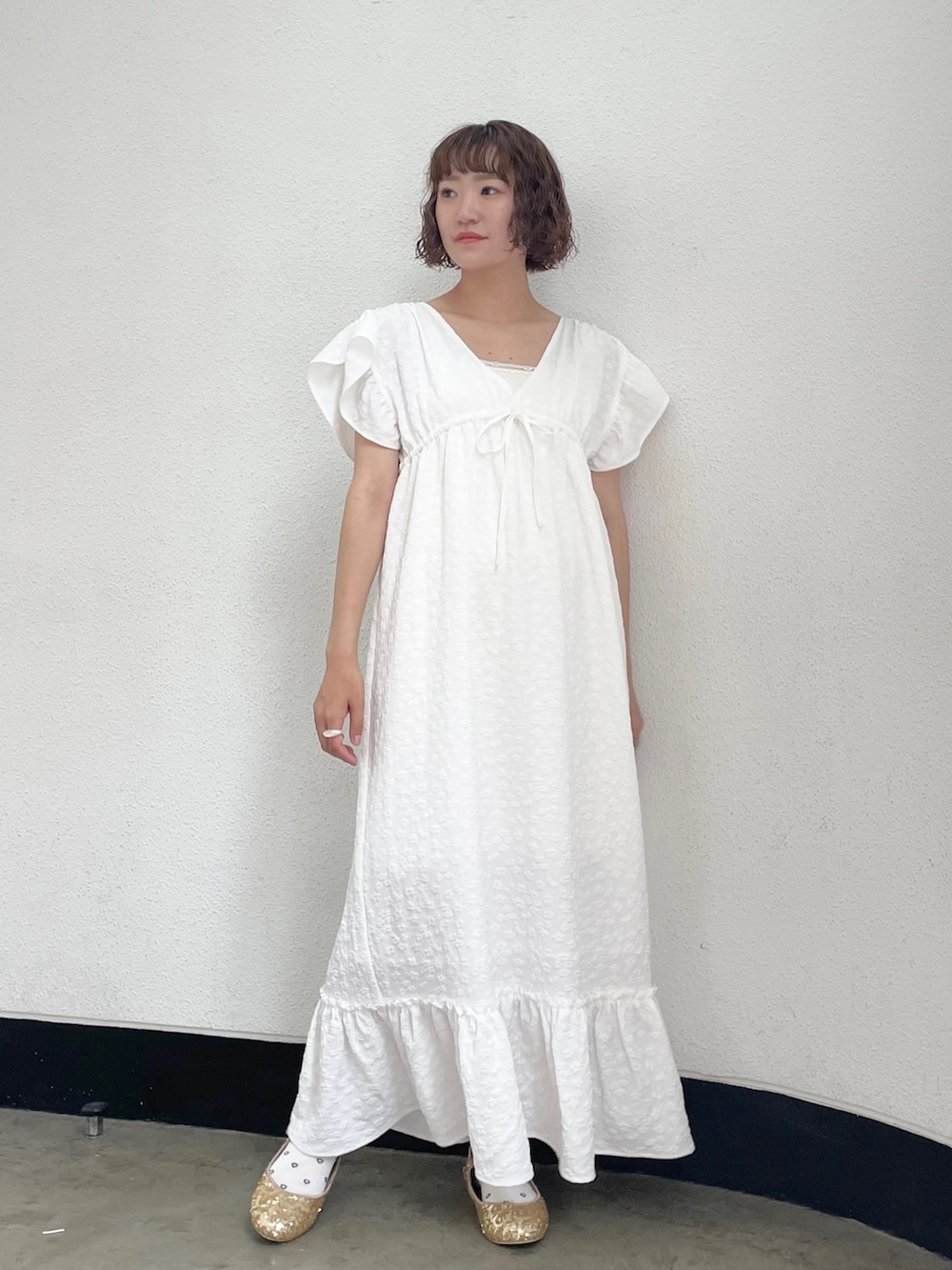 ホワイト系のキャミソール、ホワイト系のワンピース、ゴールド系のパンプスを着用したレディースの春コーディネートの2枚目の写真