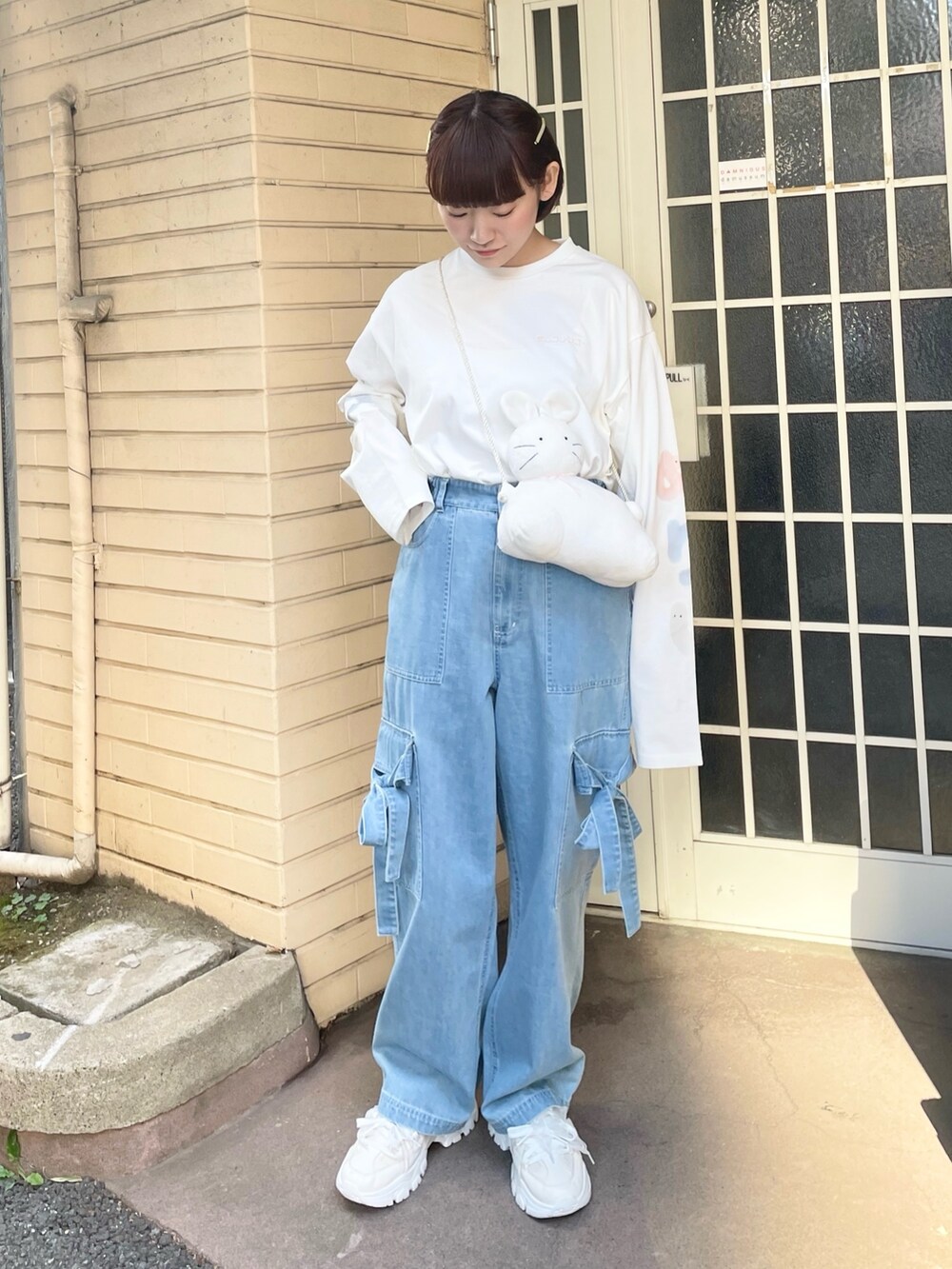 ホワイト系のTシャツ/カットソー、ホワイト系のショルダーバッグ、ブルー系のデニムパンツを着用したレディースの冬コーディネートの2枚目の写真