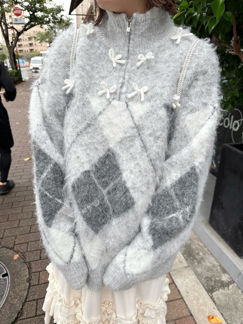 ホワイト系のスカート、グレー系のニット/セーター、ホワイト系のバックパック/リュックを着用したレディースの秋コーディネートの7枚目の写真