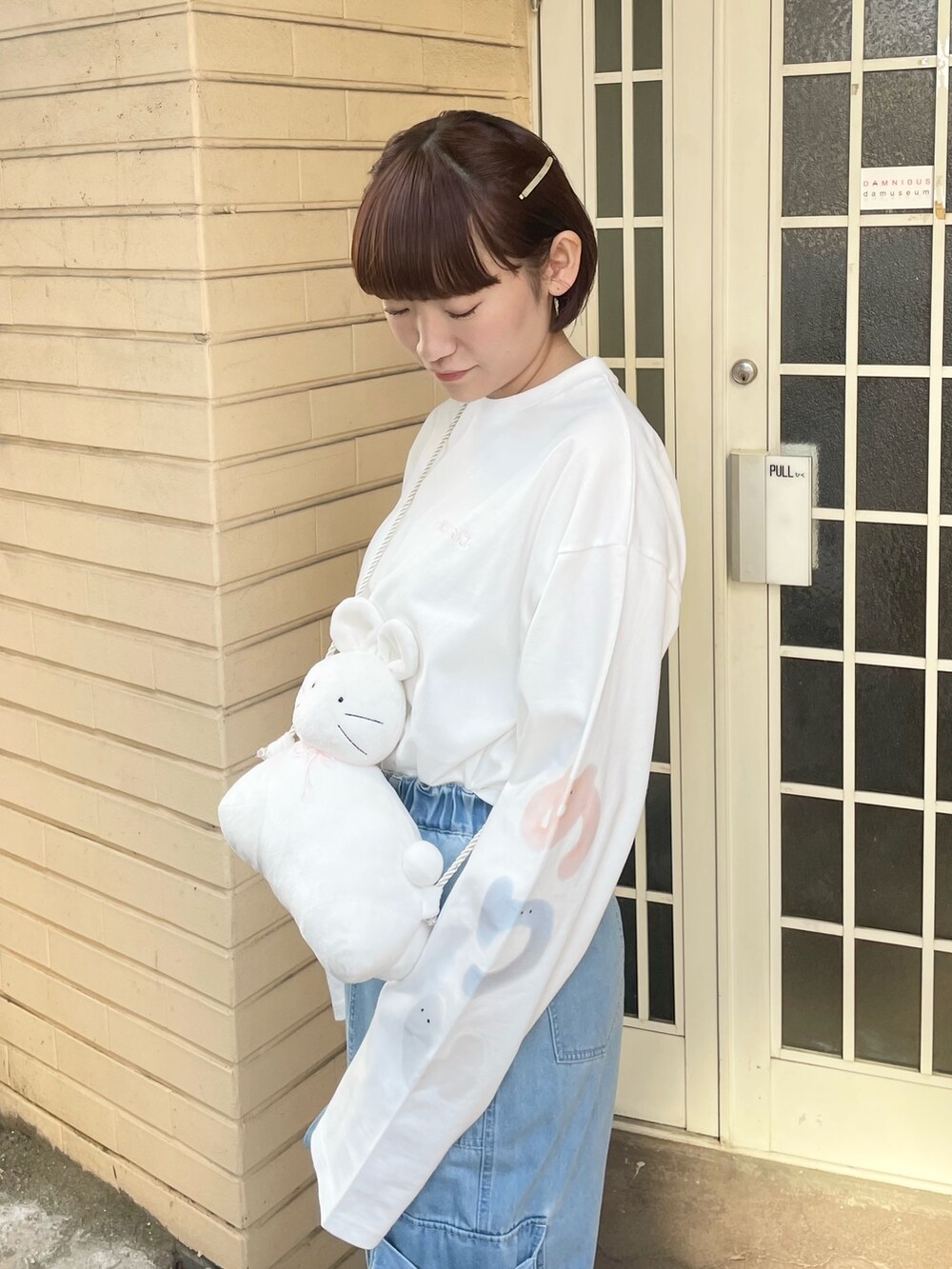 ホワイト系のTシャツ/カットソー、ホワイト系のショルダーバッグ、ブルー系のデニムパンツを着用したレディースの冬コーディネートの5枚目の写真