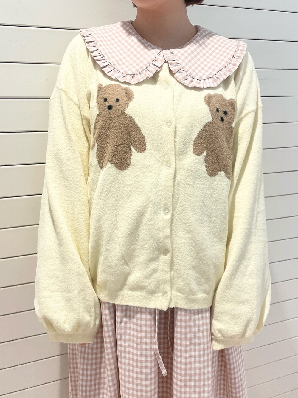 ピンク系のワンピース、ホワイト系のカーディガン/ボレロ、ホワイト系のスニーカーを着用したレディースの冬コーディネートの6枚目の写真