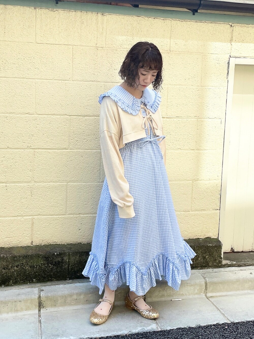 ホワイト系のカーディガン/ボレロ、ブルー系のワンピース、ゴールド系のパンプスを着用したレディースの春コーディネートの2枚目の写真