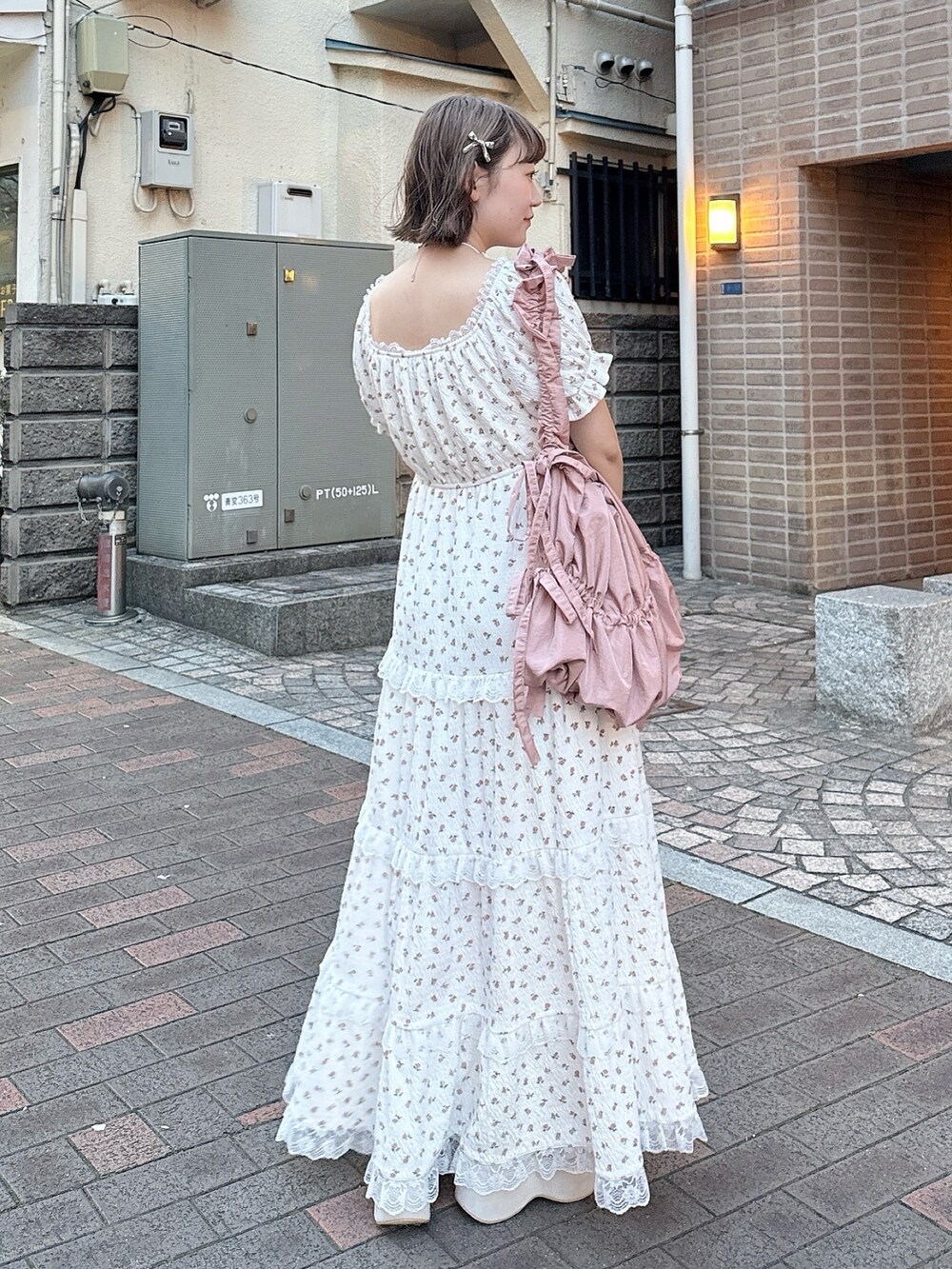 ピンク系のトートバッグ、ベージュ系のサンダル、ホワイト系のワンピースを着用したレディースの春コーディネートの4枚目の写真