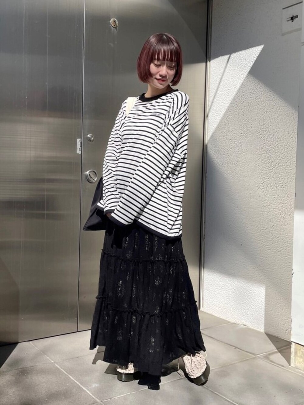 ホワイト系のその他シューズ、ブラック系のスカート、ブラック系のトートバッグを着用したレディースの春コーディネートの2枚目の写真