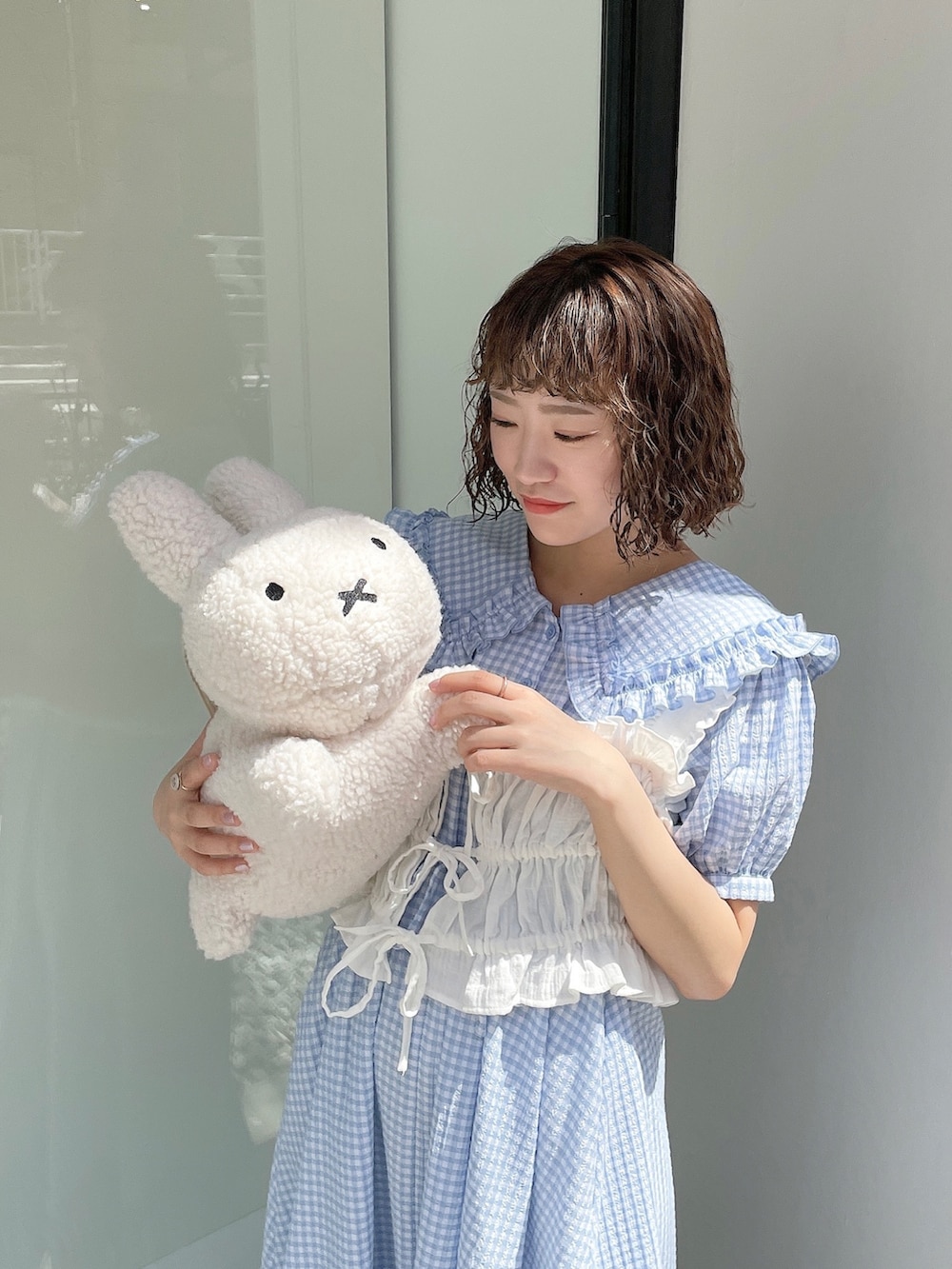 ブルー系のワンピース、ホワイト系のハンドバッグ、ホワイト系のベストを着用したレディースの春コーディネートの2枚目の写真