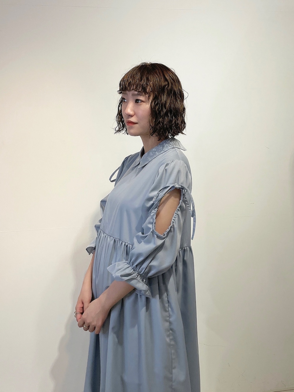 ホワイト系のトートバッグ、ブルー系のワンピース、ゴールド系のパンプスを着用したレディースの春コーディネートの5枚目の写真