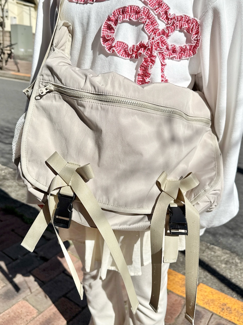 ホワイト系のスウェット、ベージュ系のメッセンジャーバッグ、ホワイト系のスウェットパンツを着用したレディースの冬コーディネートの5枚目の写真