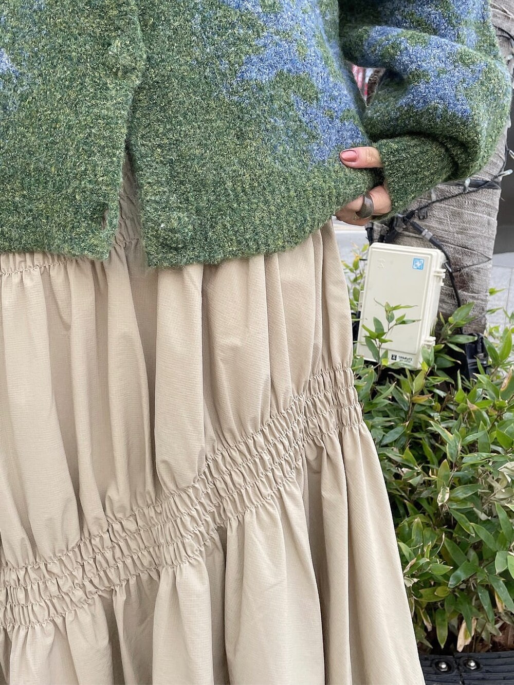 グリーン系のカーディガン/ボレロ、ベージュ系のスカート、ホワイト系のニット/セーターを着用したレディースの冬コーディネートの5枚目の写真