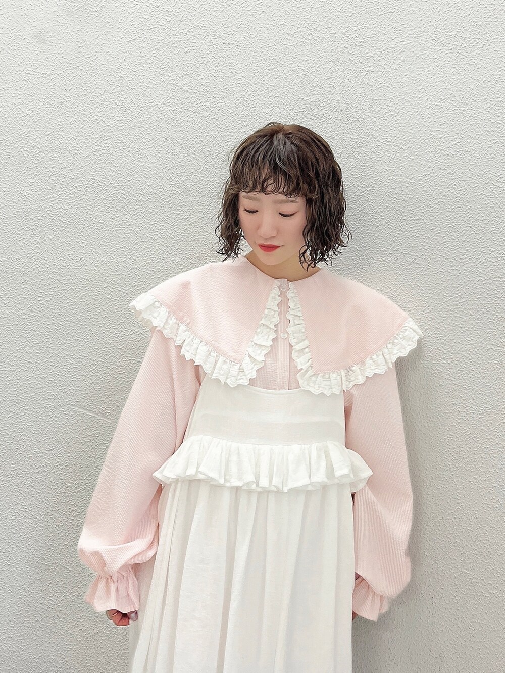 ピンク系のシャツ/ブラウス、ホワイト系のスカート、ピンク系のパンプスを着用したレディースの春コーディネートの3枚目の写真