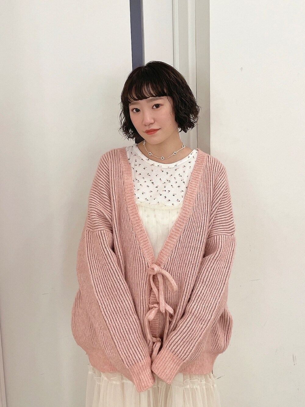 ピンク系のカーディガン/ボレロ、ピンク系のTシャツ/カットソー、ホワイト系のワンピースを着用したレディースの秋コーディネートの4枚目の写真