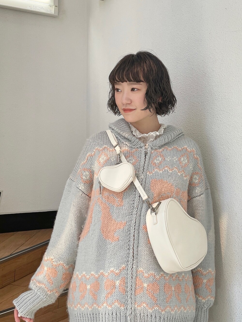 ピンク系のスニーカー、ホワイト系のジャンパースカート、ホワイト系のハンドバッグを着用したレディースの秋コーディネートの4枚目の写真
