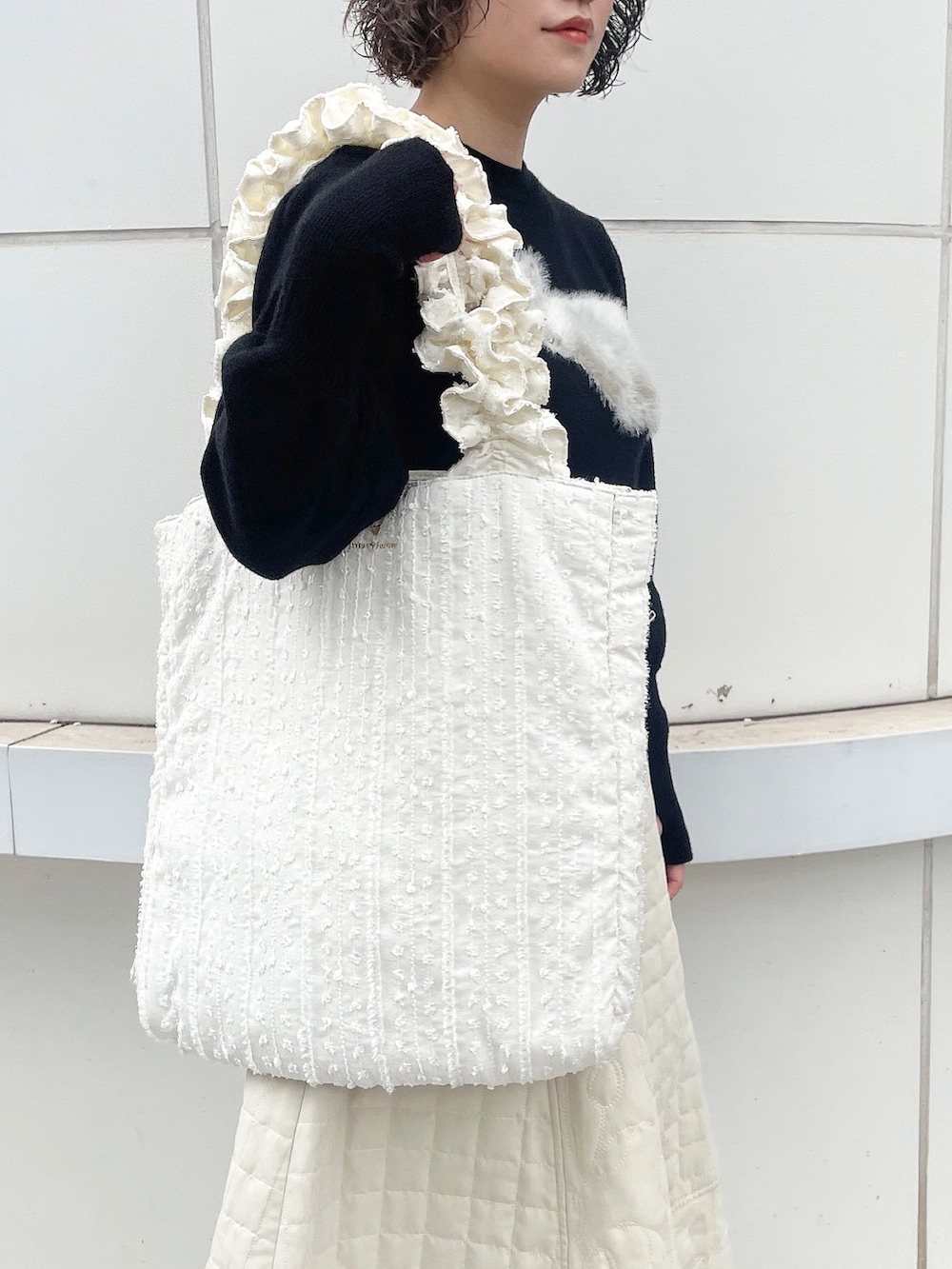 ブラック系のニット/セーター、ホワイト系のハンドバッグ、ホワイト系のスカートを着用したレディースの秋コーディネートの5枚目の写真