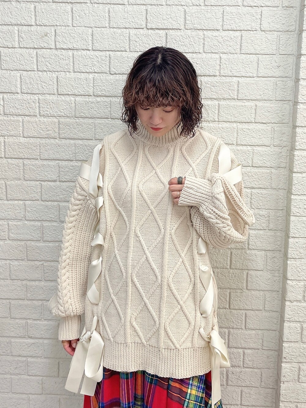 ホワイト系のニット/セーター、レッド系のスカート、ベージュ系のブーツを着用したレディースの冬コーディネートの4枚目の写真