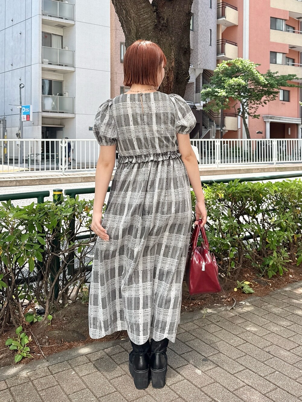 ブラック系のワンピース、レッド系のハンドバッグ、ブラック系のブーツを着用したレディースの夏コーディネートの3枚目の写真