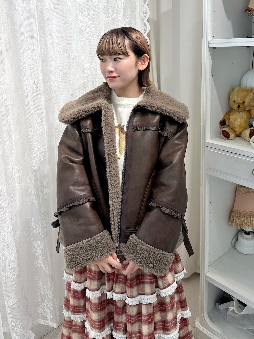ブラウン系のムートンコート、ホワイト系のニット/セーター、レッド系のスカートを着用したレディースの秋コーディネートの4枚目の写真