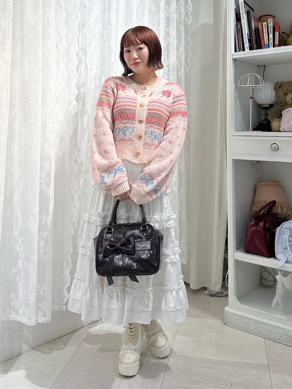 ピンク系のカーディガン/ボレロ、ホワイト系のスカート、ブラウン系のハンドバッグを着用したレディースの夏コーディネートの2枚目の写真
