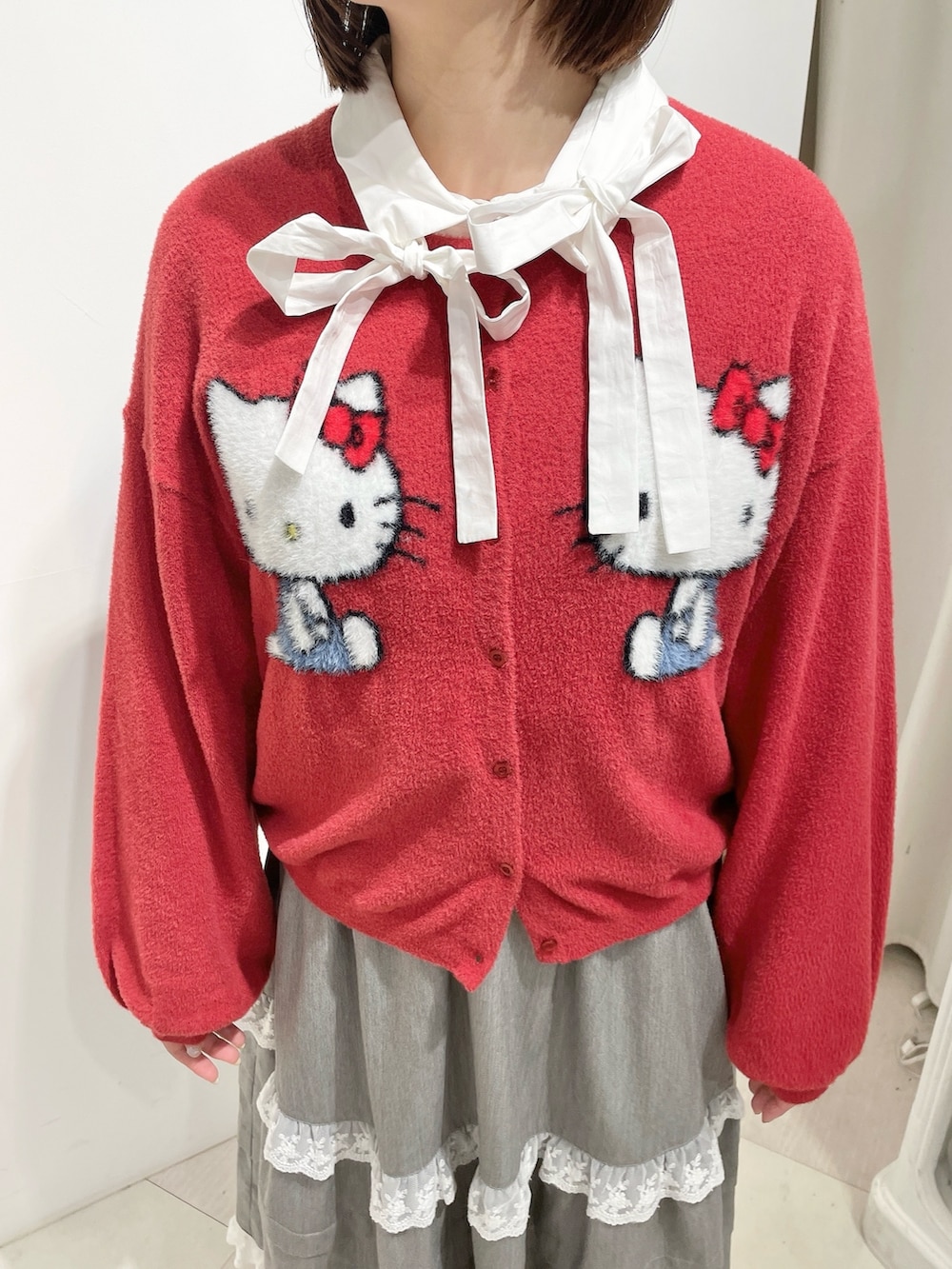 ホワイト系のシャツ/ブラウス、レッド系のカーディガン/ボレロ、グレー系のスカートを着用したレディースの秋コーディネートの6枚目の写真