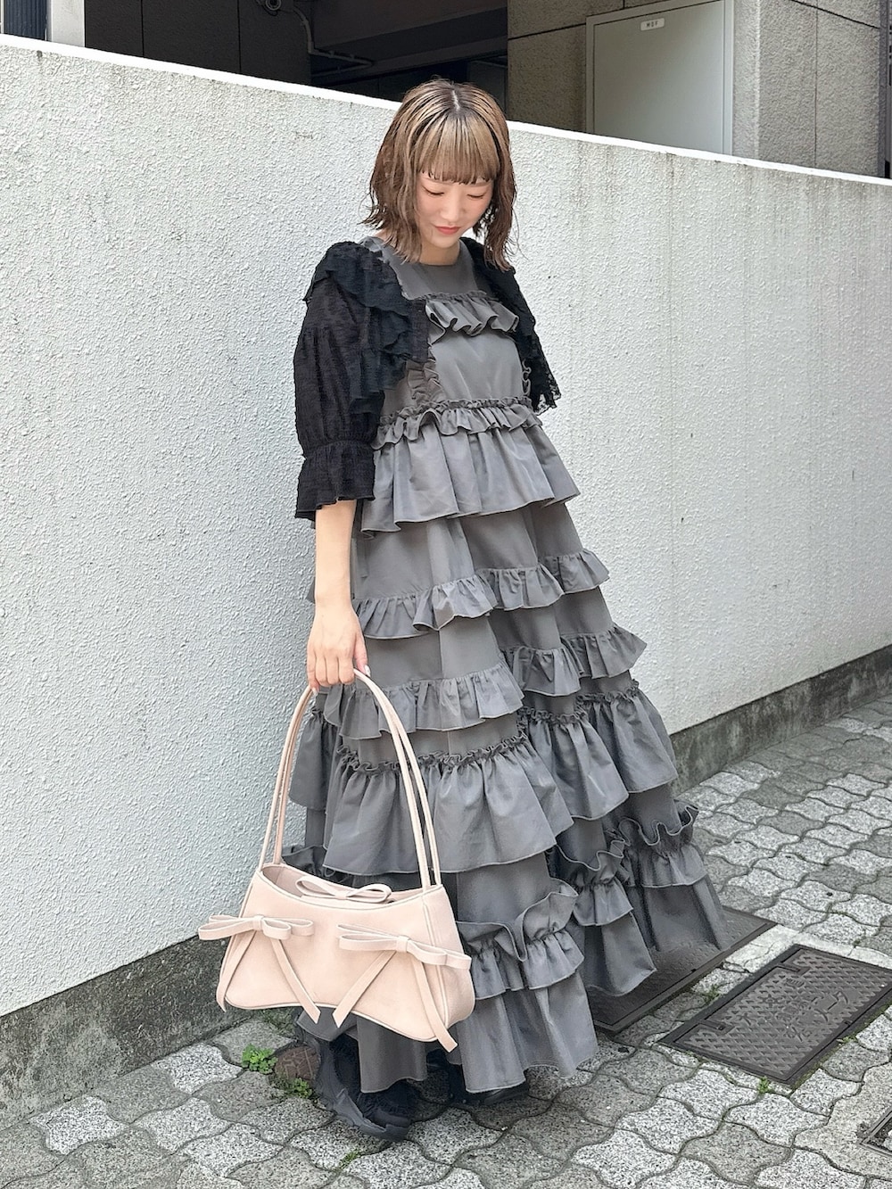 グレー系のワンピース、ブラック系のカーディガン/ボレロ、ピンク系のハンドバッグを着用したレディースの春コーディネートの2枚目の写真