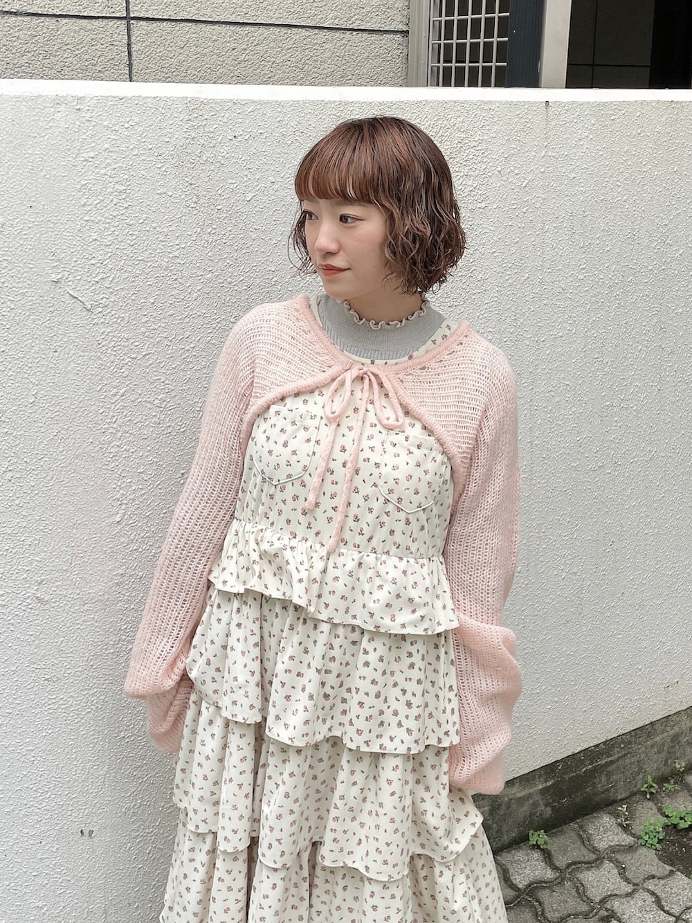 ホワイト系のジャンパースカート、ピンク系のカーディガン/ボレロ、グレー系のニット/セーターを着用したレディースの秋コーディネートの5枚目の写真