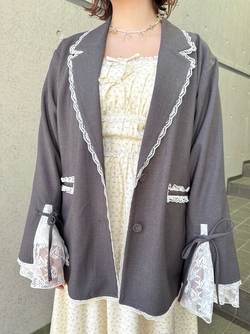 グレー系のテーラードジャケット、ベージュ系のワンピース、ホワイト系のショルダーバッグを着用したレディースの冬コーディネートの7枚目の写真