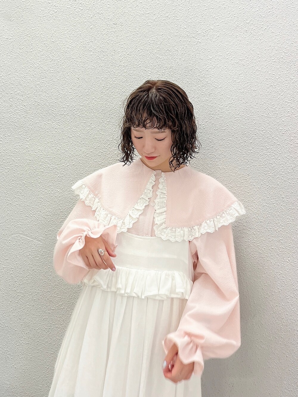 ピンク系のシャツ/ブラウス、ホワイト系のスカート、ピンク系のパンプスを着用したレディースの春コーディネートの4枚目の写真