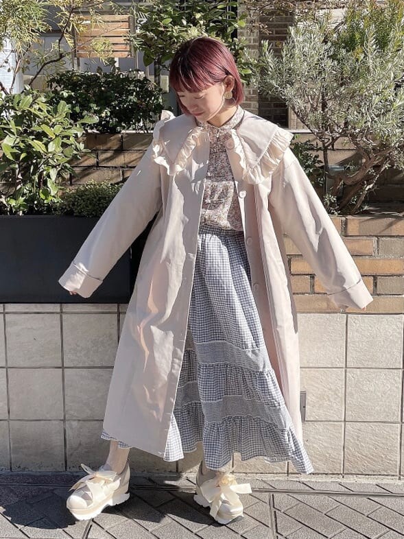 ホワイト系のトレンチコート、オレンジ系のシャツ/ブラウス、ブルー系のスカートを着用したレディースの冬コーディネートの6枚目の写真