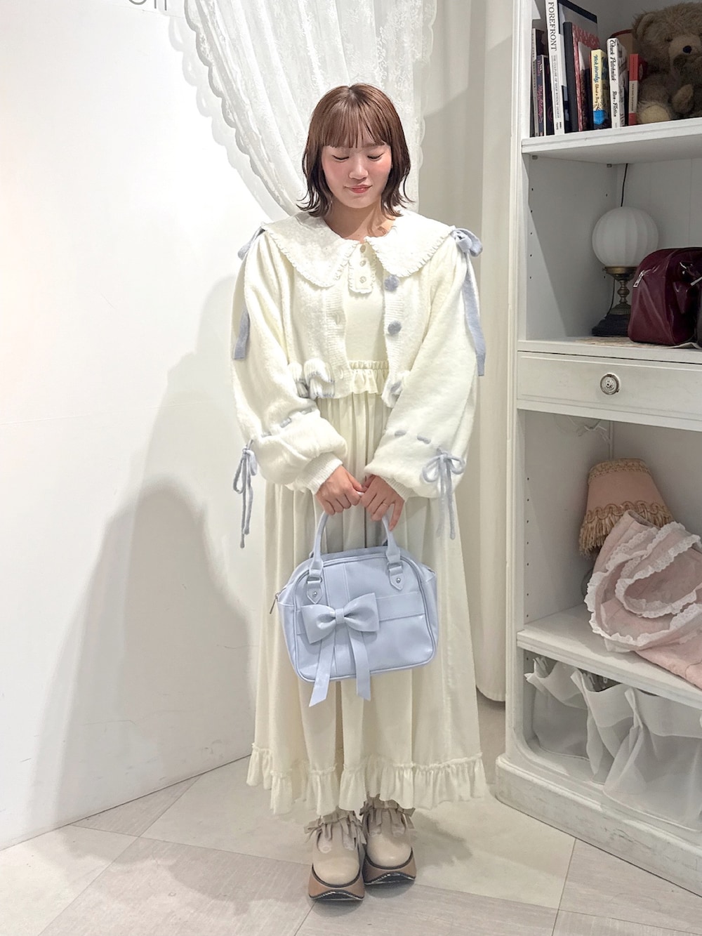 ホワイト系のワンピース、ホワイト系のカーディガン/ボレロ、ブルー系のハンドバッグを着用したレディースの秋コーディネートの2枚目の写真
