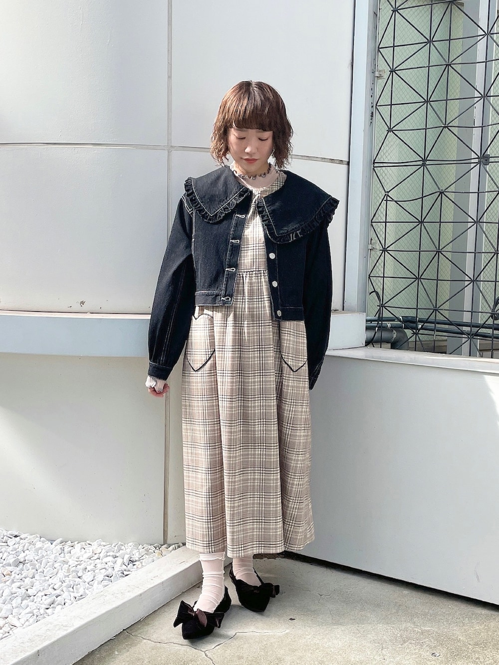 ピンク系のニット/セーター、ブラック系のデニムジャケット、ベージュ系のワンピースを着用したレディースの夏コーディネートの2枚目の写真